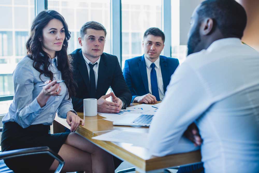 Business professionals meeting with a client to review financial reports and discuss strategy, representing expert transaction guidance and strategic planning through M&A Advisory California services.