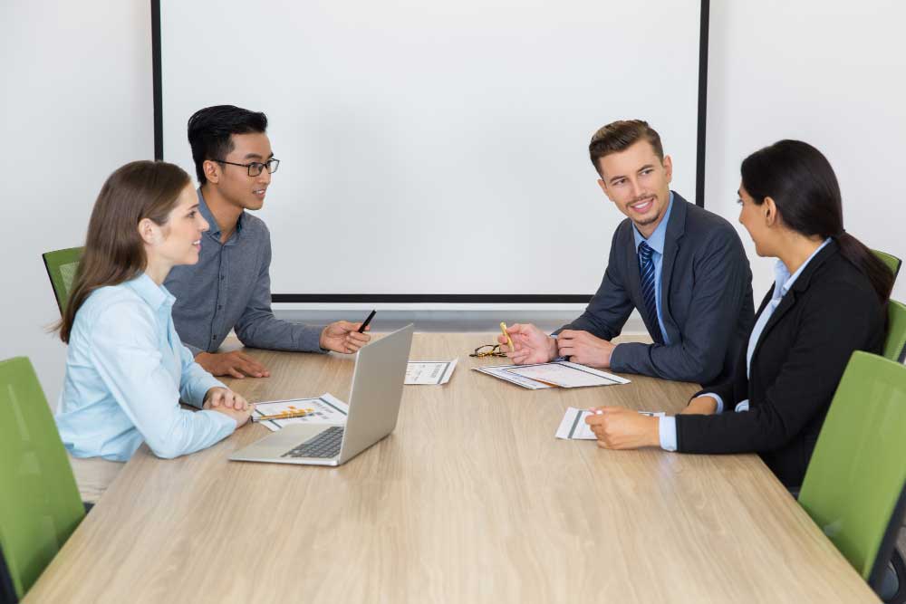 Group of business professionals collaborating in a meeting with a laptop and documents on the table, representing strategic planning and expert financial guidance through M&A Advisory Chicago services.