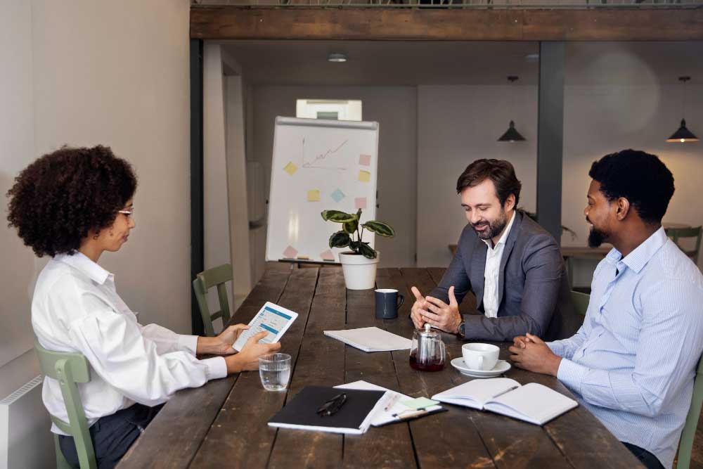 Business professionals meeting at a conference table reviewing reports and discussing strategy, representing collaborative planning and expert financial guidance through M&A Advisory Chicago services.