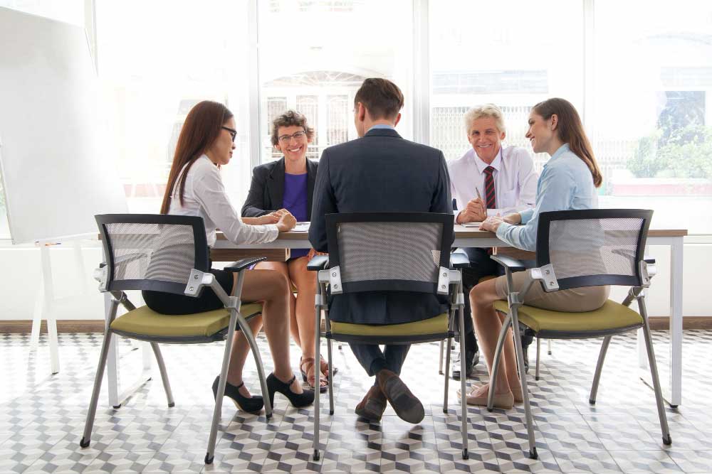 Business professionals seated around a conference table discussing strategy in a bright office setting, representing collaborative financial planning and expert transaction guidance through M&A Advisory Florida services.