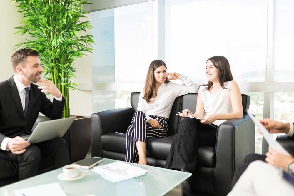 Business professionals having a strategy discussion in a modern office lounge setting, representing collaborative financial planning and expert transaction support through M&A Advisory Maryland services.