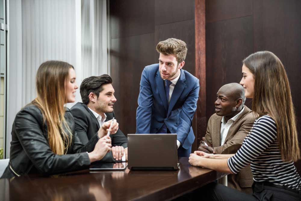 Business team collaborating around a laptop in a conference room, discussing financial strategy and transaction planning with expert guidance from M&A Advisory Maryland services.
