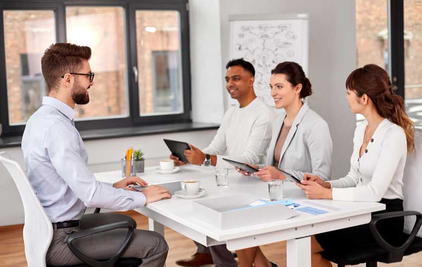 Business professionals conducting an interview and reviewing documents in a modern office, representing strategic planning and expert transaction support through M&A Advisory New Jersey services.