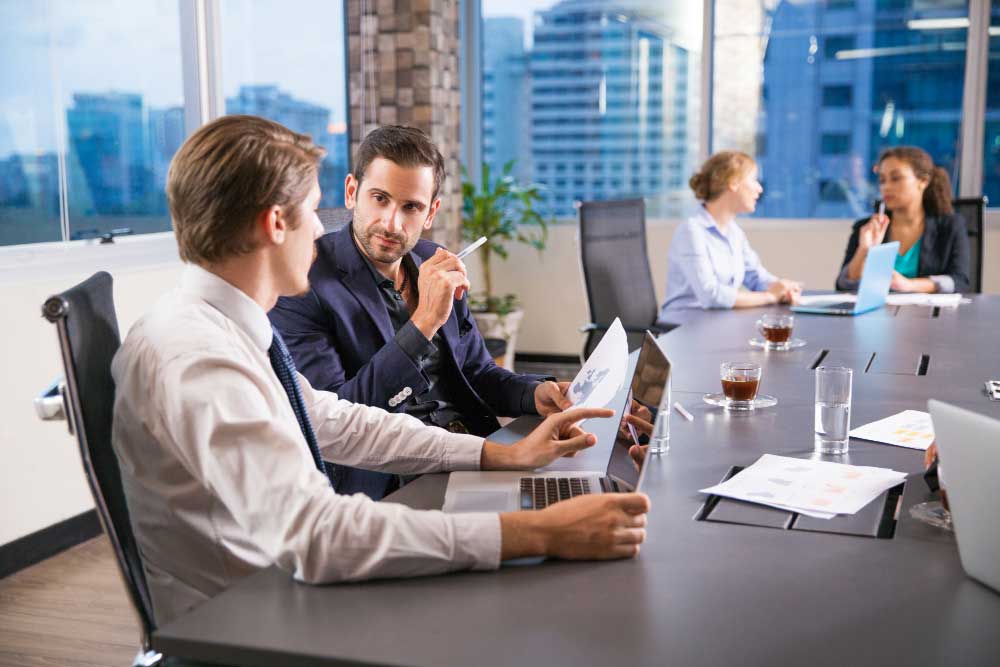 Business executives discussing financial reports and strategy in a modern conference room, representing expert transaction guidance and strategic planning through M&A Advisory New Jersey services.