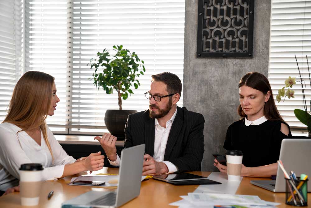 Business professionals discussing financial documents and strategy in a modern office meeting, representing expert consultation and transaction support through M&A Advisory New York services.