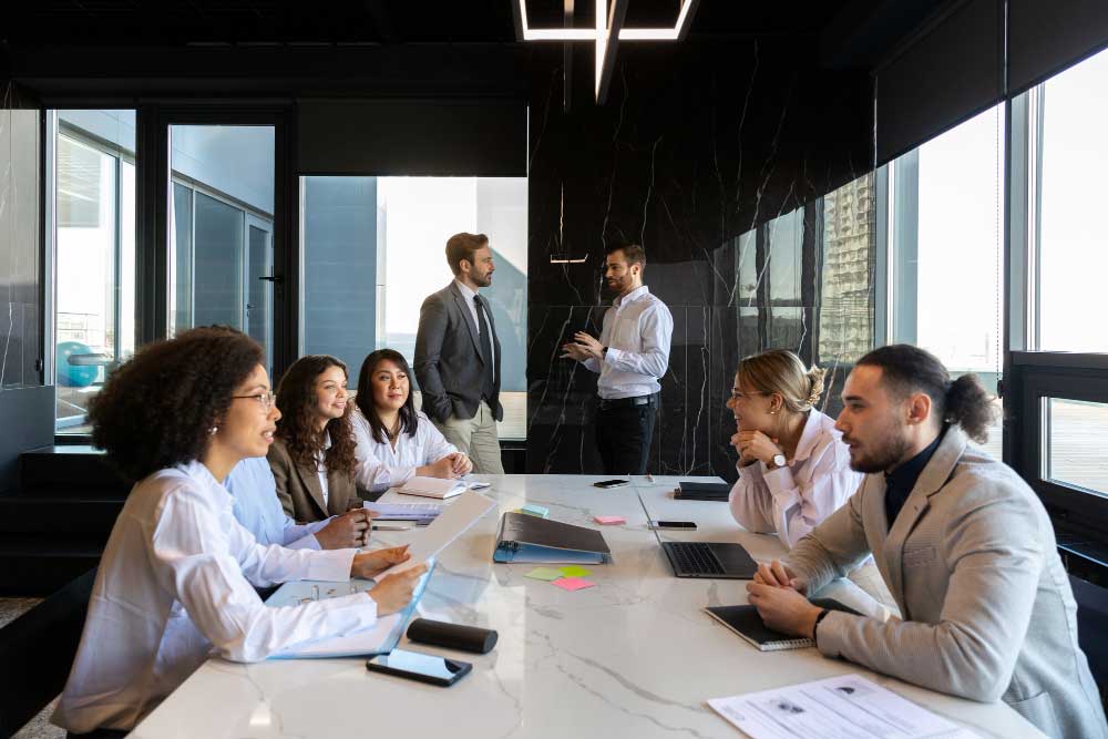 Business consultants meeting with a client at a desk reviewing documents and discussing strategy, representing professional financial guidance and transaction support through M&A Advisory Pennsylvania services.