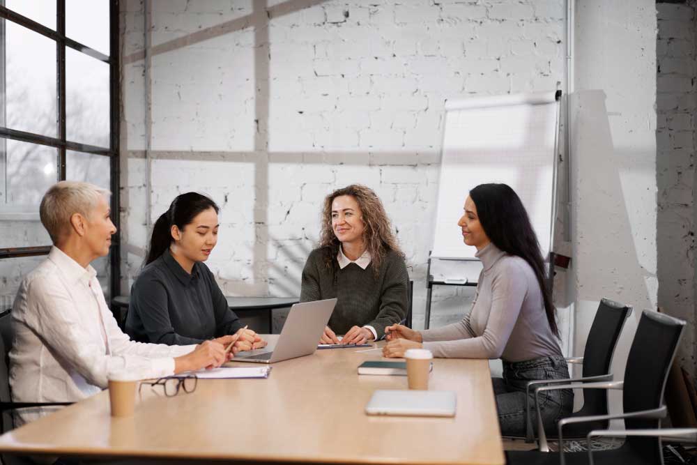 Business professionals meeting around a conference table with a laptop and documents, discussing strategy and financial planning with expert guidance from M&A Advisory Tennessee services.