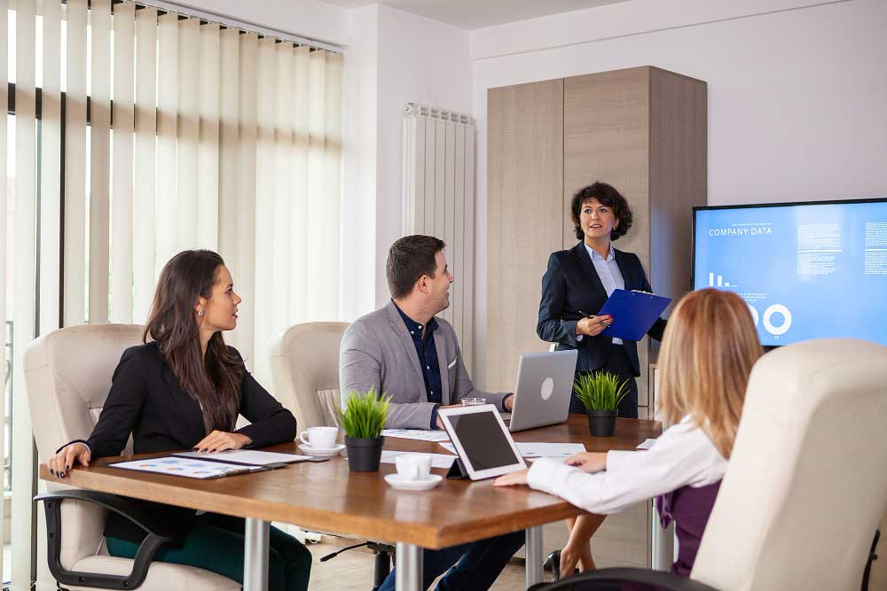 Business advisor consulting with a smiling couple during a professional meeting at an office desk, M&A Advisory Tennessee
