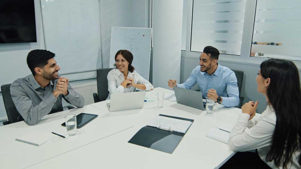 Business consultant smiling during a meeting with a client across a laptop in a modern office, representing strategic planning and expert transaction guidance through M&A Advisory Washington services.